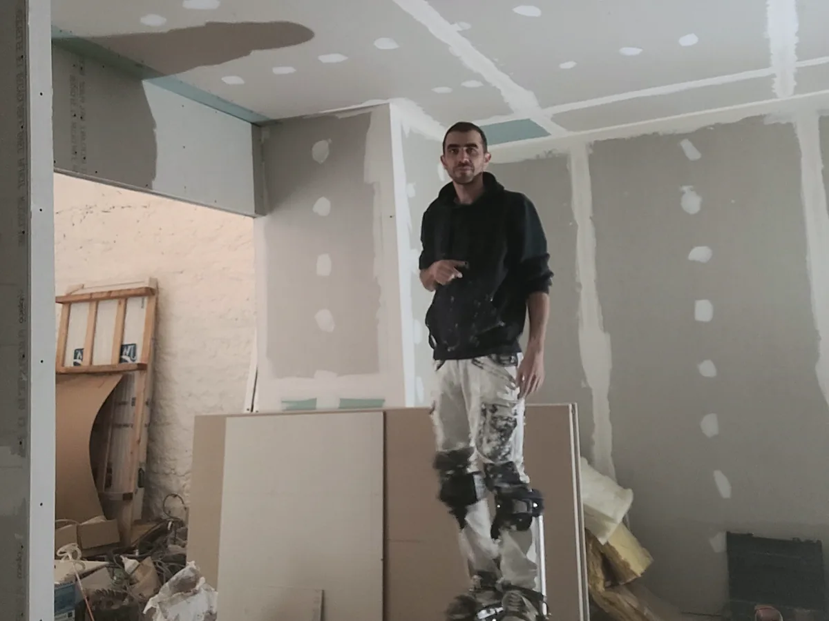 Artisan plaquiste sur échasses pendant la réalisation d’un plafond